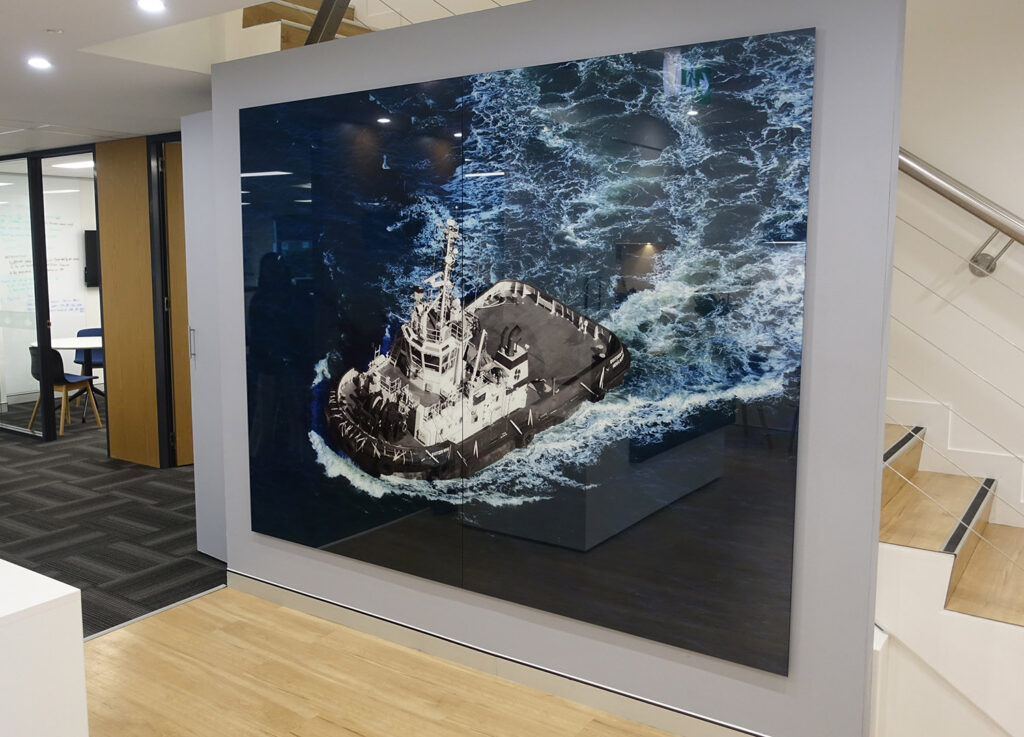 Large tugboat ocean scene created with high-quality glass printing on an office wall