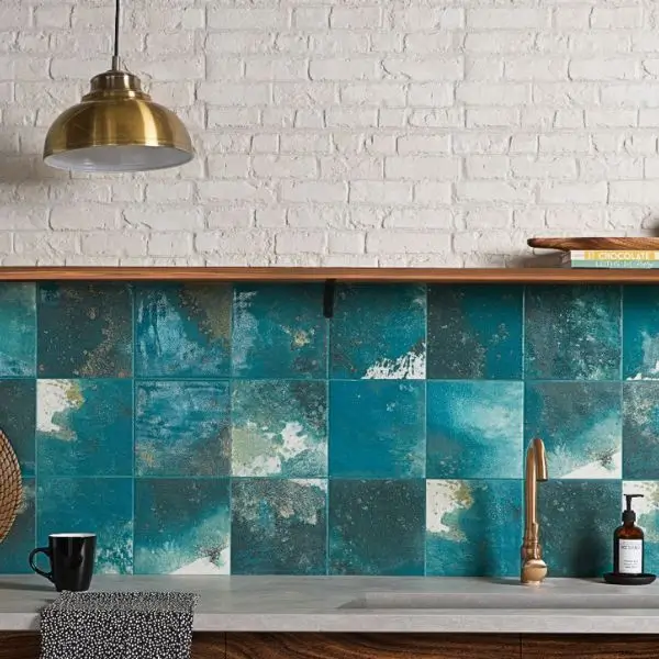 Chic kitchen interior design Dubai featuring teal textured tiles and a gold pendant light