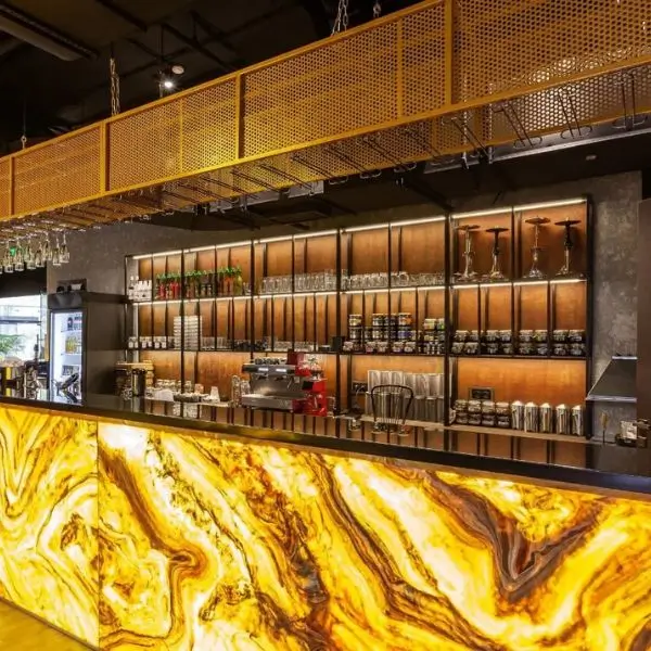 Luxury bar interior design Dubai featuring a backlit marble counter and industrial shelving